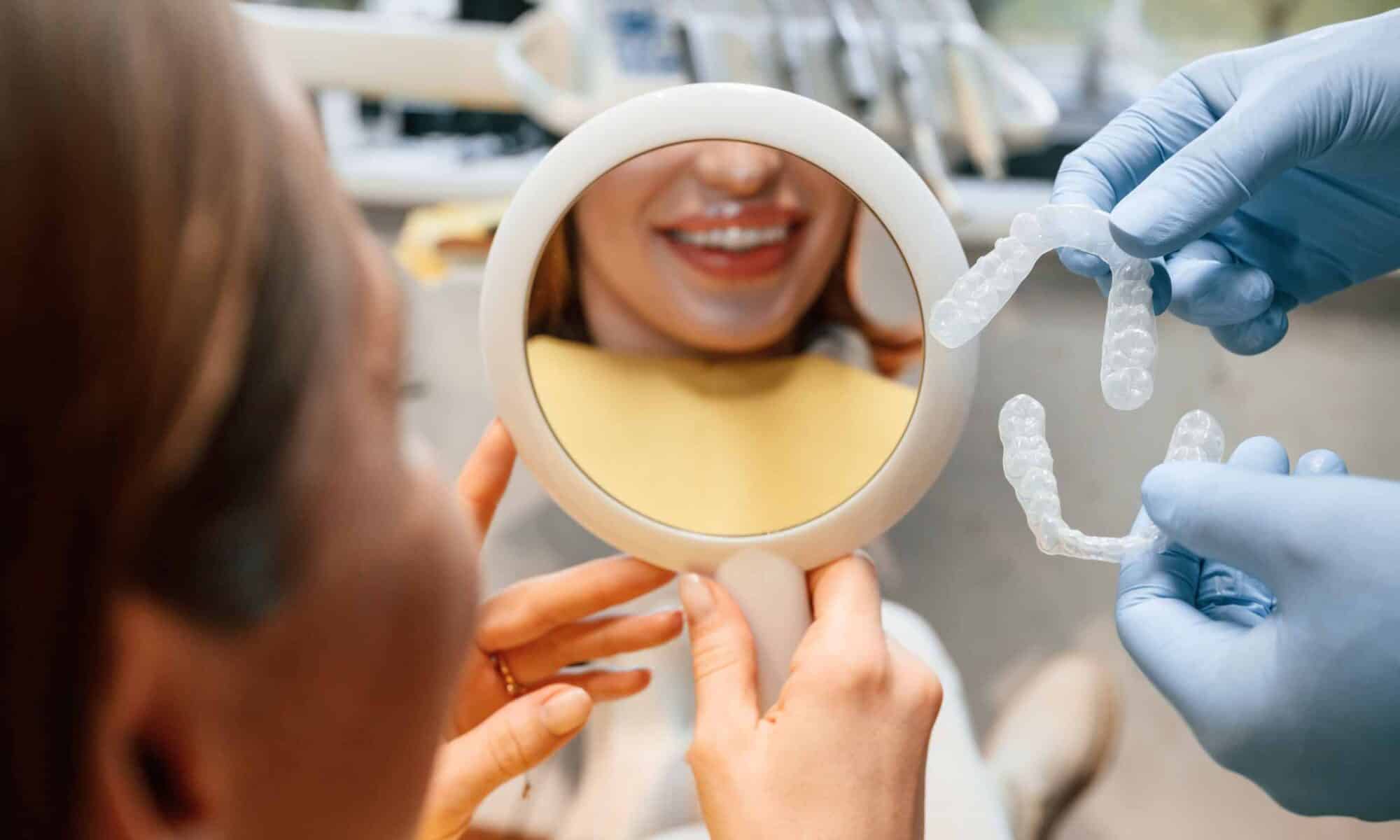 Patient viewing her smile while an orthodontist presents clear aligners for Invisalign in Merrick